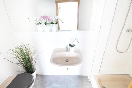 a white bathroom with a sink and flowers on the wall at Downtown Apartments Ulm - im Herzen von Ulm & komfortable Boxspringbetten in Ulm