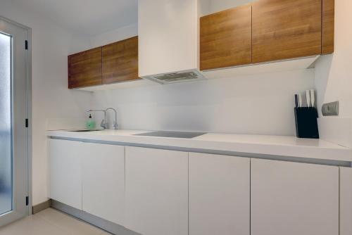 a white kitchen with a sink and wooden cabinets at Aqua Apartments Vento, Marbella in Marbella