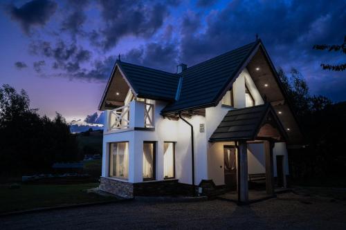 a white house with a black roof at night at Modrzewiowa Ostoja in Kluszkowce