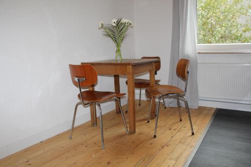 une table avec trois chaises et un vase sur elle dans l'établissement Apartment Wostspitze, à Bochum