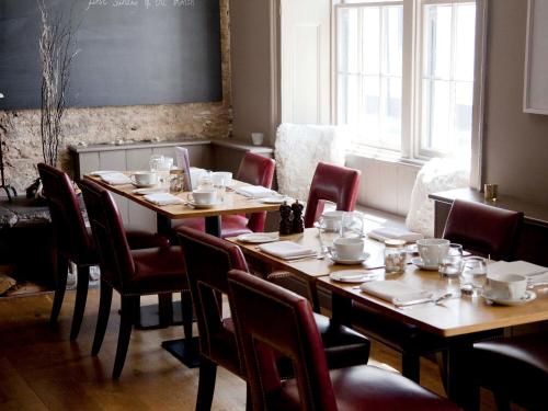 a dining room with wooden tables and red chairs at The Archangel,Restaurant & Bar with Rooms in Frome