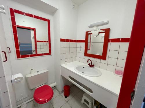 a red and white bathroom with a sink and a toilet at Le Surf in Mimizan-Plage