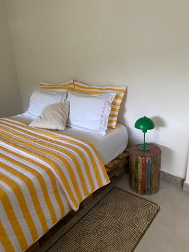 ein Schlafzimmer mit einem Bett und einer grünen Lampe auf einem Tisch in der Unterkunft Cantinho na natureza perto das praias in Niterói