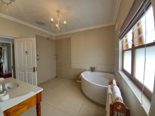 a bathroom with a bath tub and a sink at La Pension Guest House in Oudtshoorn