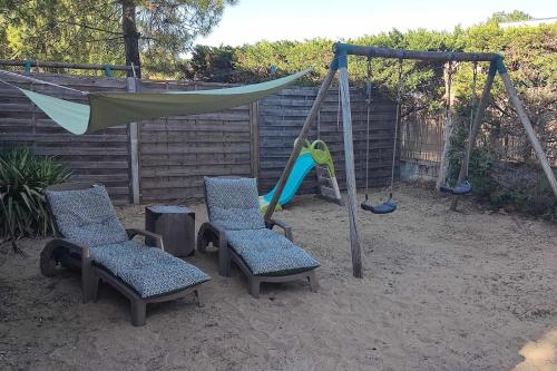 einen Spielplatz mit Stühlen, einer Hängematte und einer Schaukel in der Unterkunft Spacious quiet nest with garden near the sea in La Tranche-sur-Mer