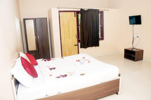 a bedroom with a white bed with red pillows at Grass dew in Yercaud