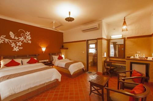 a hotel room with two beds and a desk at Green Park Chitwan in Sauraha