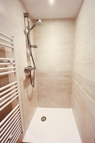 une salle de bain avec une douche avec pommeau de douche dans l'établissement Appart au centre de la station, entièrement rénové, , parking privé et wifi gratuit, à Les Deux Alpes