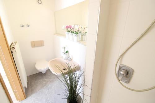 a bathroom with a sink and a toilet and flowers at Downtown Apartments Ulm - im Herzen von Ulm & komfortable Boxspringbetten in Ulm