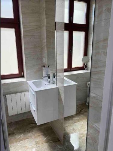 ein weißes Badezimmer mit einem Waschbecken und einem Spiegel in der Unterkunft Apartament w centrum Inowrocławia in Inowrocław