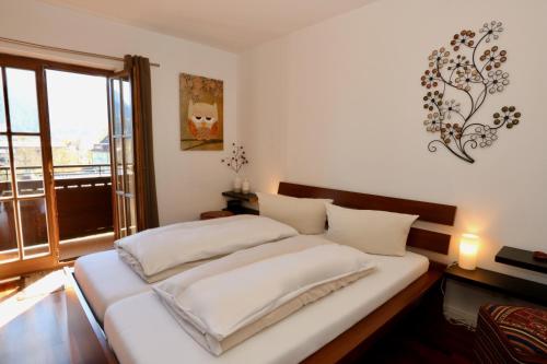 um quarto com uma cama com lençóis brancos e uma janela em Central Pearl em Garmisch-Partenkirchen