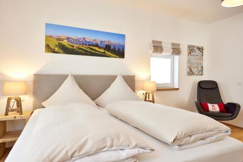um quarto com uma cama branca e uma cadeira em BergJuwel em Garmisch-Partenkirchen
