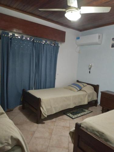 a bedroom with two beds and a window with blue curtains at Casa Magali in Federación