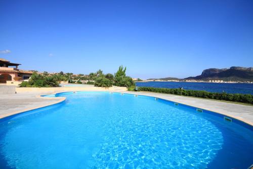 una gran piscina azul junto a un cuerpo de agua en S'Abba e Sa Pedra, en Golfo Aranci