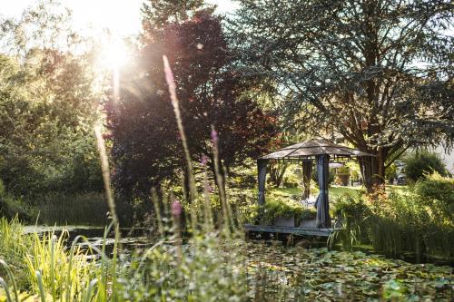 un jardín con cenador en medio de un estanque en Romantik Hotel & Restaurant Stafler, en Vipiteno
