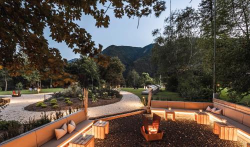 a park with benches and trees and mountains in the background at Romantik Hotel & Restaurant Stafler in Vipiteno