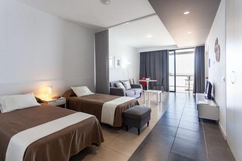 Habitación de hotel con 2 camas y sofá en RentOnTheBeach Studio 2 en Los Cristianos