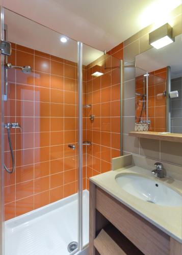 La salle de bains est pourvue de carrelage orange, d'une douche et d'un lavabo. dans l'établissement Villages Clubs du Soleil - LES 2 ALPES, à Les Deux Alpes