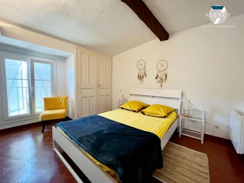 - une chambre avec un lit avec des draps jaunes et une chaise dans l'établissement Le Tropezien, à Grimaud