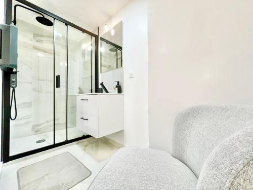 uma casa de banho branca com um chuveiro e um sofá em LE ROSACKER - Proche centre ville et gare - Terrasse - Parking gratuit 2 places - 2 chambres - 2 salles de bain em Colmar