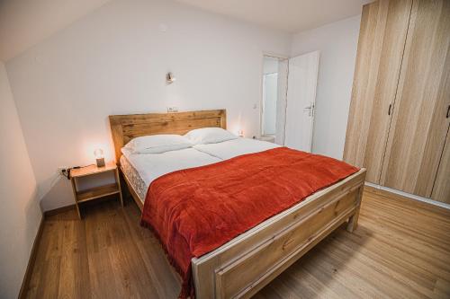 a bedroom with a large bed with a red blanket at Mojčin Pisker Apartment House in Kranj