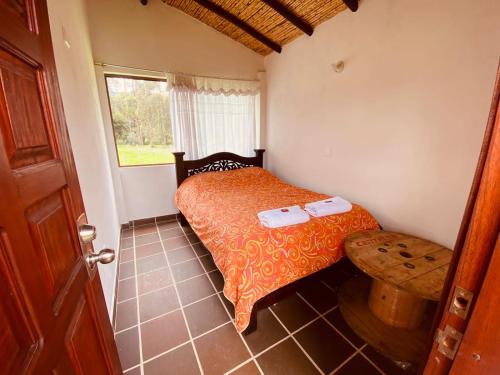 a small bedroom with a bed and a window at Cabaña Campestre - Ciudad Memoria in Sogamoso