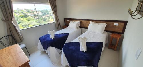 a bedroom with two beds with blue sheets and a window at Refúgio Escarpas do Lago in Capitólio