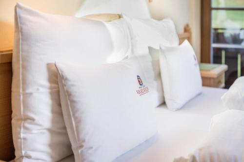 a pile of white pillows on a bed at Haus zur Vogelweide App 5 in Dobbiaco