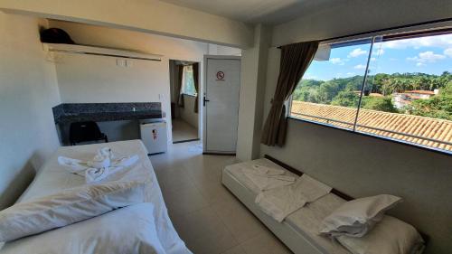 a bedroom with two beds and a large window at Hotel Escarpas do Lago Capitolio in Capitólio