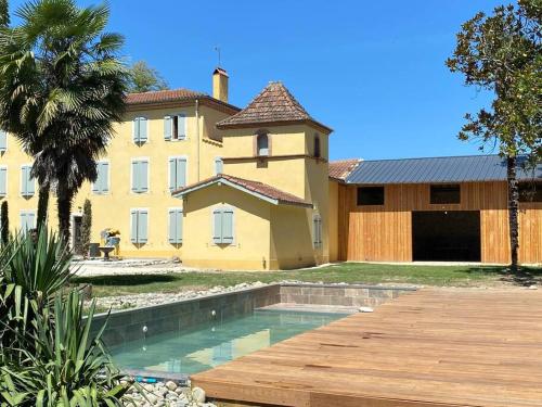 una gran casa amarilla con piscina frente a ella en Domaine des Airs de Toscane, en Cazères