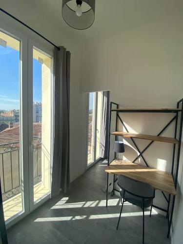 - un bureau et une chaise dans une chambre avec fenêtres dans l'établissement Bel appartement T1 30m2 centre historique Aubagne, à Aubagne