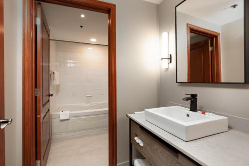 ein Badezimmer mit einem weißen Waschbecken und einem Spiegel in der Unterkunft Sommet Des Neiges in Mont-Tremblant