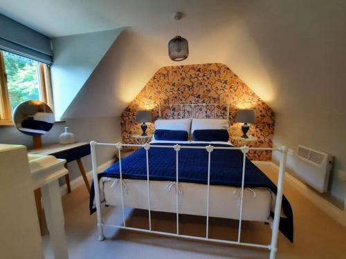 a bedroom with a white bed with a blue comforter at The Hen Den in Hopton Cangeford