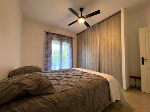a bedroom with a ceiling fan and a bed at Villa au calme tout confort in Lapalud
