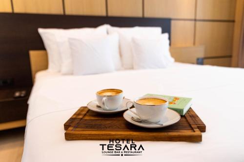 two cups of coffee on a wooden tray on a bed at Hotel Tesara in Prizren