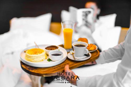 a table with a tray of food and orange juice at Hotel Tesara in Prizren