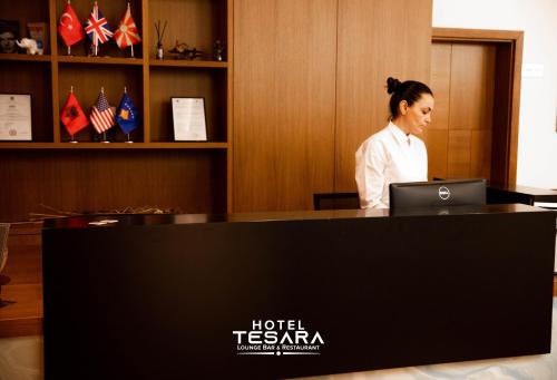 a woman standing in front of a desk with a laptop at Hotel Tesara in Prizren