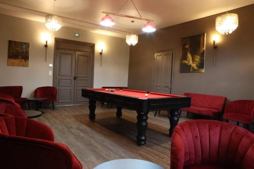 Cette chambre comprend une table de billard et des chaises rouges. dans l'établissement Château de Petit Bois, à Cosne-dʼAllier