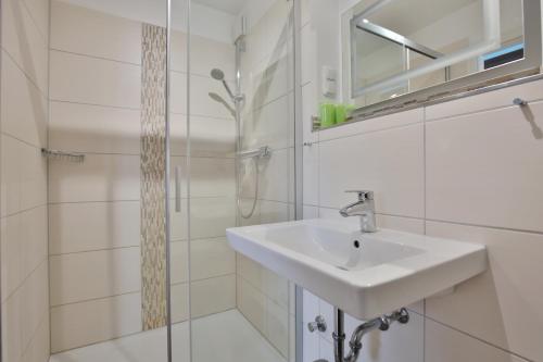 a white bathroom with a sink and a shower at Haus Miramar TREF Appartement 64 in Niendorf