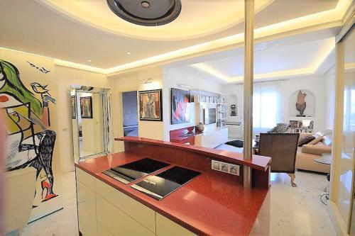 - une cuisine avec un comptoir rouge dans le salon dans l'établissement Palais Miramar Suite Art Modern - Derniere étages Vue Mer - 75m de confort - En Face des Plages -WIFI - Clim, à Cannes