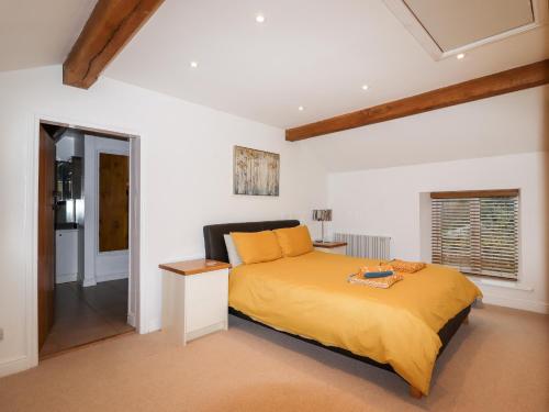 a bedroom with a bed with a yellow bedspread at South Hillswood Farm in Leek
