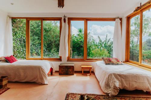 2 camas en una habitación con ventanas grandes en Designers Luxury Retreat with breathtaking gardens, en Tzununá