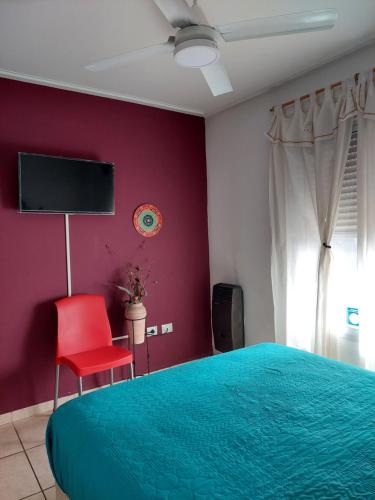 - une chambre avec un lit et un mur rouge dans l'établissement Departamento Viamonte con cochera, à Bahía Blanca