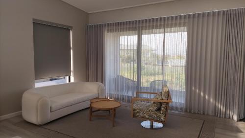 a living room with a couch and a large window at Hilltop Bayview Luxury Apartments in Plettenberg Bay