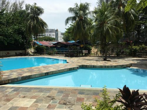 una gran piscina azul con palmeras en el fondo en The Rockview Bayu Emas Penang Near Beach en Batu Ferringhi