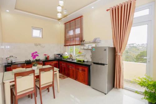 Il comprend une cuisine équipée d'un réfrigérateur, d'une table et de chaises. dans l'établissement Villa Trung Nghĩa 16, à Đà Lạt