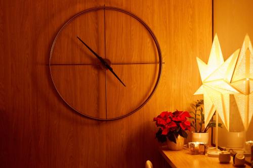 a clock on a wall next to a table with flowers at Kamilkowy Apartament in Karpacz