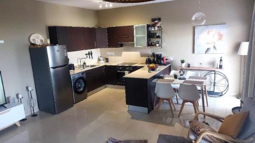 a kitchen with a refrigerator and a table with chairs at Paramount Gardens Resorts C202 in Larnaka
