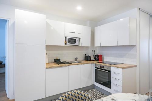 a white kitchen with white cabinets and a microwave at Elégant - Hypercentre - Croisette - Palais - AK in Cannes