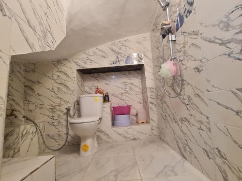 - une salle de bains avec toilettes dans une chambre aux murs en marbre dans l'établissement بالوما, à Temara